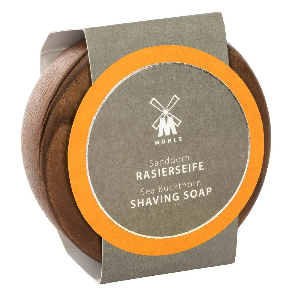 Housed in a round wooden container, this plastic-free package features a windmill logo on the lid and a gray and orange label reading “Mühle Sanddorn Rasierseife Sea Buckthorn Shaving Soap.” Inside is premium Mühle Sea Buckthorn Shaving Soap, enriched with seabuckthorn for a refreshing shave.