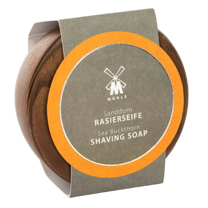 Housed in a round wooden container, this plastic-free package features a windmill logo on the lid and a gray and orange label reading “Mühle Sanddorn Rasierseife Sea Buckthorn Shaving Soap.” Inside is premium Mühle Sea Buckthorn Shaving Soap, enriched with seabuckthorn for a refreshing shave.