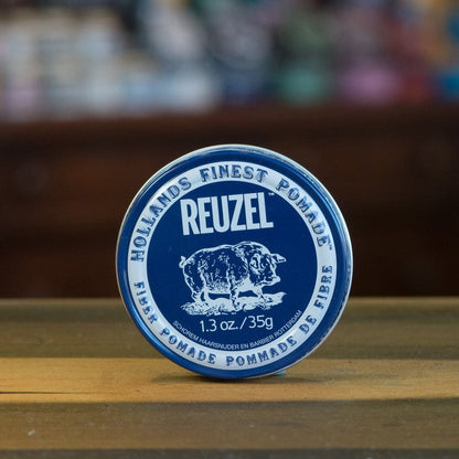 Reuzel Fiber Pomade Navy tin on wood, ideal for medium-thick hair, offering medium-strong hold and light shine for natural, textured styles.