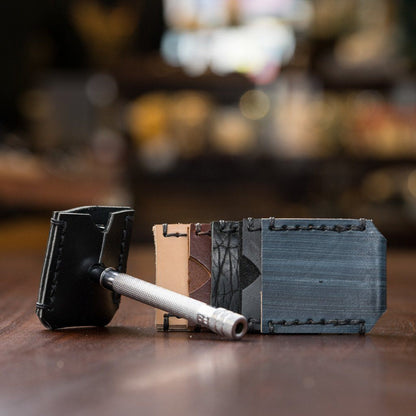 Horace & Jasper DE Safety Razor Head Cover displayed with a metal safety razor and various colored leather blade sleeves on a wooden surface.