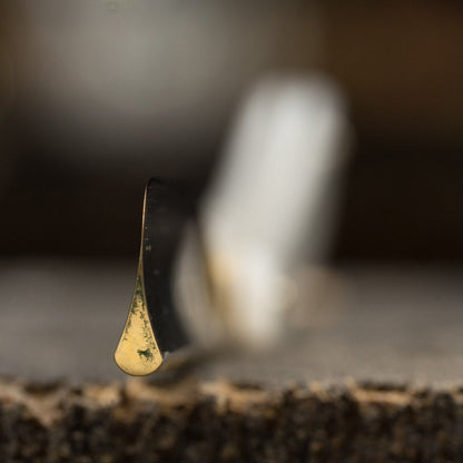 Close-up of a Dovo Pearl Straight Razor’s imitation pearl handle with a droplet on the aged brass faucet near a granite countertop, highlighting craftsmanship.