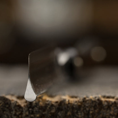 Close-up of Dovo Astrale Straight Razor's tip with liquid droplet on blade, showcasing precision craftsmanship with Swedish carbon steel and ebony handle.