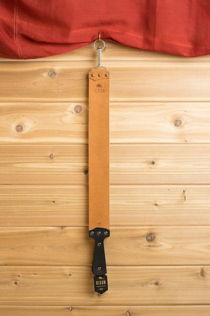 Ezra Arthur Natural Horsehide strop hanging, showcasing its durable tan leather strap and metal fittings, ideal for enhancing straight razor sharpness and longevity.