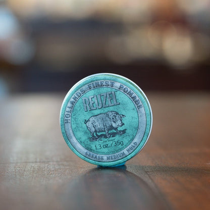 Reuzel Grease Medium Green, a 1.3 oz tin of classic medium-hold pomade, sits on a wooden surface, ideal for slick-back styles with lasting shine.