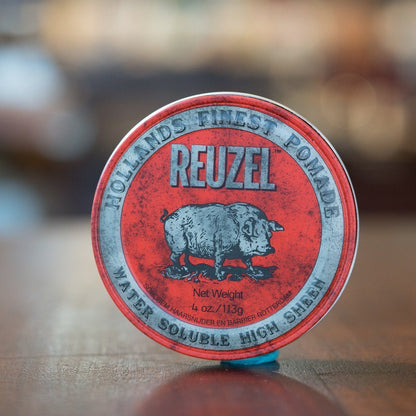 Reuzel Pomade Regular Red tin, featuring a pig illustration, offers high-shine, medium hold for all hair lengths. Ideal for classic styles, washes out easily.