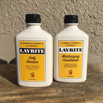 Layrite Moisturizing Conditioner, 10 fl oz, sits beside Layrite Daily Shampoo on wood; designed to hydrate and strengthen hair without weighing it down.