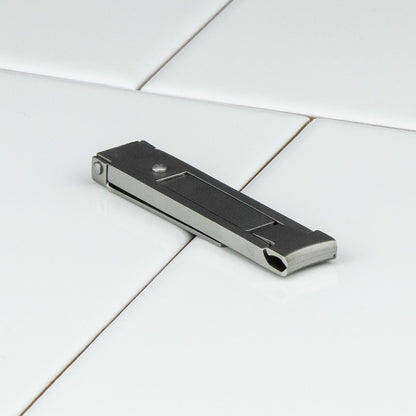 Niegeloh Inox High Carbon Stainless Steel Nail Clipper in Matte, a compact, sleek multi-tool on a white tiled surface, featuring a foldable design for easy travel use.