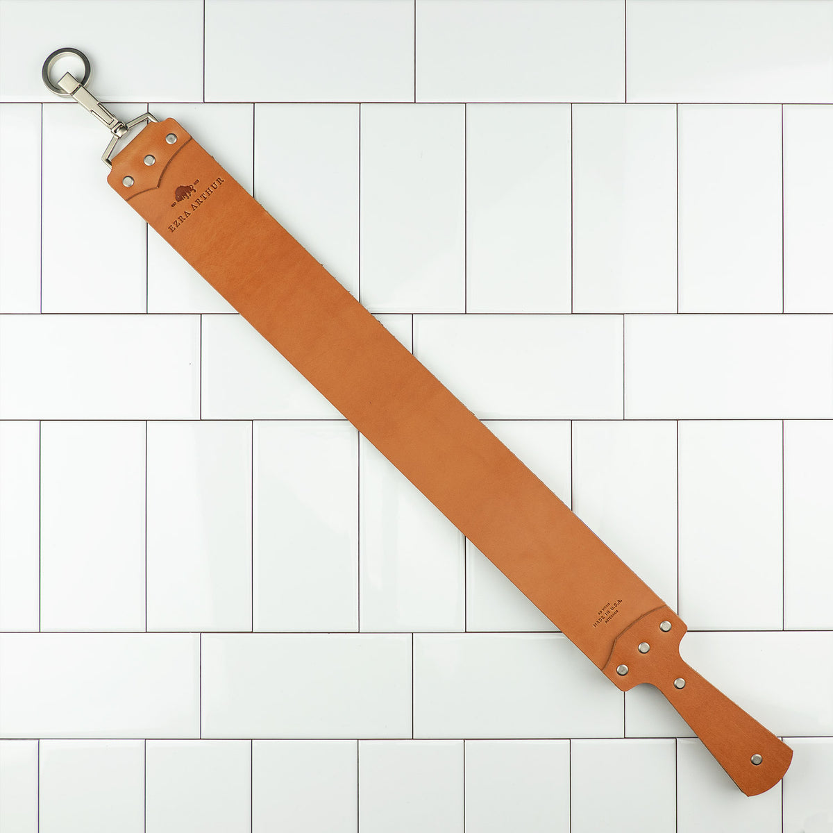 Ezra Arthur English Bridle Strop, a two-sided tan leather honing strap with handle and hanging ring, ideal for refining straight razor edges.