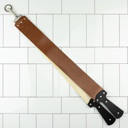 Ezra Arthur Cordovan strop with metal hanging ring, brown leather strap, canvas backing, and black handles, designed for honing and polishing straight razors effectively.
