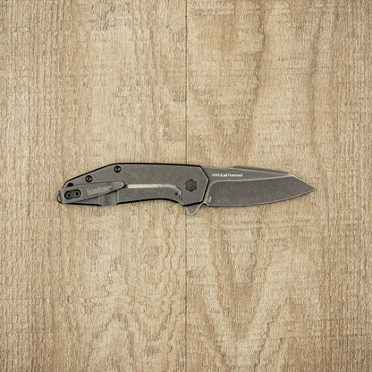 Kershaw Gravel folding pocket knife with dark stonewashed handle and drop-point blade, laid open, showcasing 2065 KAI Patented marking, ideal for daily, durable use.