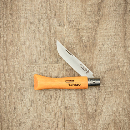 Opinel Carbon No.05 Folding Knife partially open, showing carbon-steel blade and beech-wood handle with OPINEL engraving on wood surface, embodying timeless design and craftsmanship.
