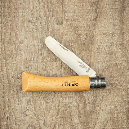Opinel Inox No.07 Kids Safety Folding Knife with a wooden handle and stainless steel blade, partially opened on a wooden surface.