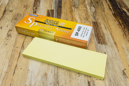 Naniwa Specialty/Super Stone 8000 210x70x10mm on wooden surface next to retail box, ideal for refining blades with ease and precision.