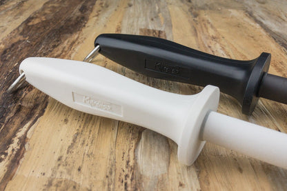 Knifewear White Ceramic Honing Rod and Black Rod on wood surface; ideal for maintaining knife edges like Powdered Steel. Features plastic guard and metal ring.