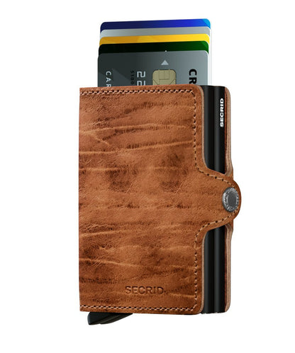 Secrid Wallets Twinwallet: Compact brown leather card-holder with RFID-blocking, featuring a metal carrier fanning four cards for stylish, secure organization. Hand-made in Holland.