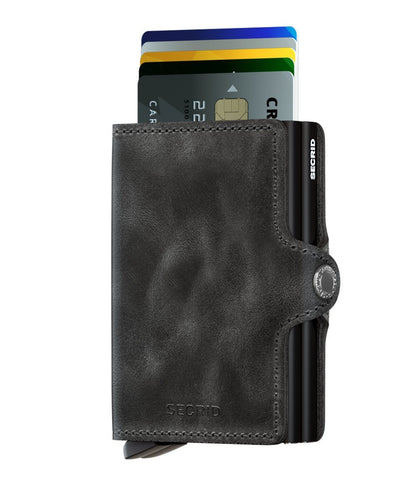 Secrid Wallets Twinwallet: Black leather wallet with metal card-holder, fanning cards via bottom lever. Features snap-button strap, RFID blocking, holds 10-12 cards. Hand-made in Holland.