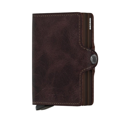 Secrid Wallets Twinwallet, a dark brown leather cardholder with a pop-out card mechanism, snap-button closure, and RFID protection, offering sleek organization for 10-12 cards.