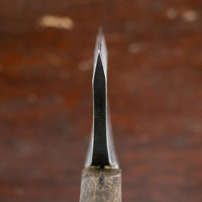 Mizuno Bakin Bearded Hatchet blade close-up, featuring a thin, sharpened edge for carving and bushcraft, with a wooden handle partially visible.