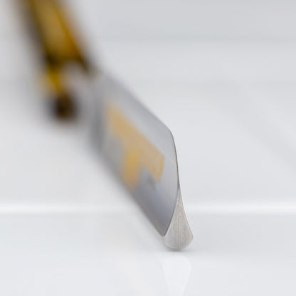 Macro view of Dovo Special Straight Razor's 5/8” Swedish Carbon Steel blade, with imitation tortoiseshell handle slightly out of focus, reflecting classic Victorian design.