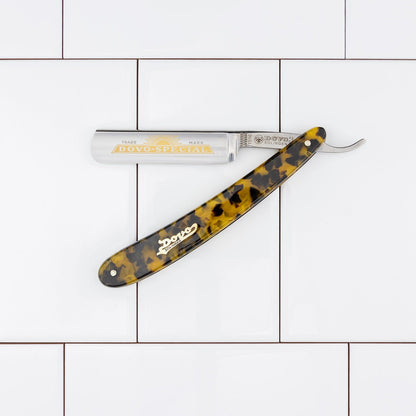 Dovo Special Straight Razor with a 5/8 Swedish Carbon Steel blade and imitation tortoiseshell handle, featuring a gold Dovo logo, laid open on tiles.