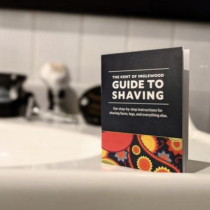The Kent of Inglewood Guide to Shaving booklet on a sink, detailing shaving techniques and tool care for faces, legs, and more.