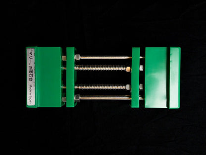 Stone Holder Spring Loaded: A portable vise-style jig with green jaws on steel rods, ideal for securely holding sharpening stones, reflecting precision and ease of use.