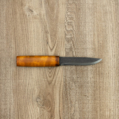 Helle Knives Viking 110mm Carbon Steel Hunting Knife with a straight blade and amber-finished wooden handle, lying on a wooden surface.