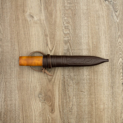 Helle Knives Viking 110mm Carbon Steel Hunting Knife with wooden handle, sheathed in brown leather, displayed on a tabletop. Ideal for utility and durability.