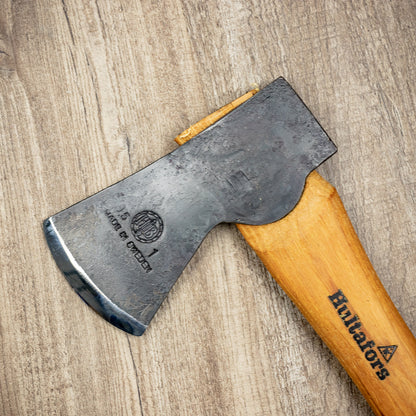 Hultafors Agelsjon Mini Hatchet with a forged steel head and American hickory handle, ideal for hiking and campsite tasks, laid on a wooden surface.
