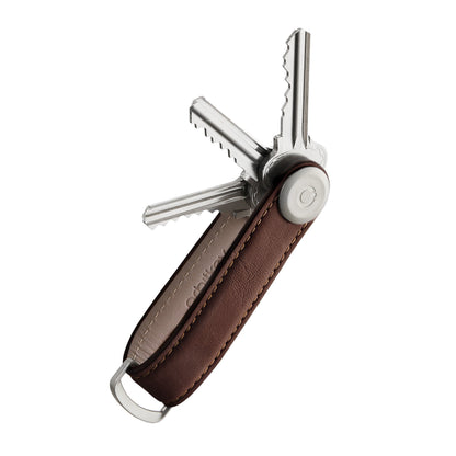 Orbitkey Leather Key Organizer with a brown leather strap and metal hardware, displaying several fanned-out metal keys, designed for tidy, silent carry of 2-7 keys.