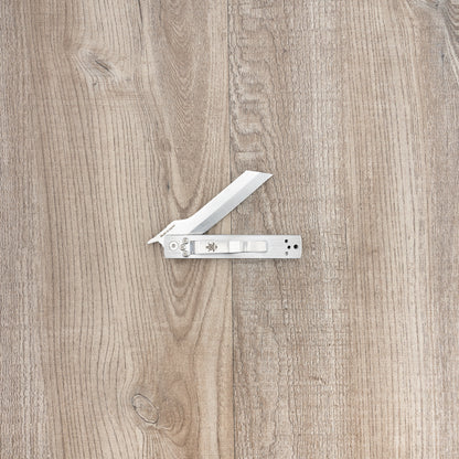Seki Kanetsune Tanzaku-Tou Folding Knife 72mm, featuring a tanto-style blade and slim metal handle with repositionable clip, displayed open on a wooden surface.
