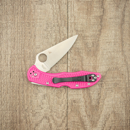 Spyderco Delica 4 Lightweight Pink S30V Folding Knife with textured FRN handle and ambidextrous clip, showcasing a sleek, open blade on a wood surface.