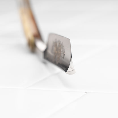 Thiers Issard Straight Razor, Gold Medallion Rams Horn, 5/8, features a wooden handle, showcased on a white tiled surface, epitomizing classic elegance and craftsmanship.