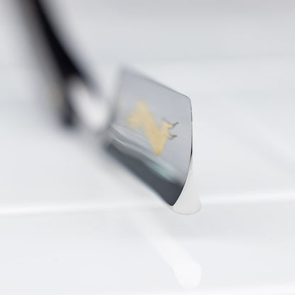 Close-up of Thiers Issard Straight Razor, Throat Cutter Gold, showcasing the shiny blade edge and gold lion emblem on a white tiled surface.