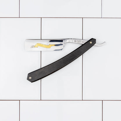 Thiers Issard Straight Razor, Throat Cutter Gold, Ebony, 6/8, featuring a polished steel blade with gold stamp, and ebony wood handle, open on tiles.
