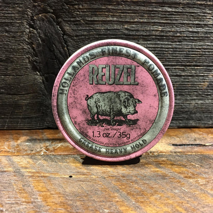 Reuzel Grease Heavy Pink pomade tin on wood surface, offering extreme hold and low-medium shine for versatile hair styles and classic grooming.